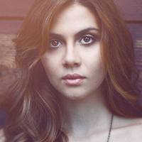 Close-up portrait of a young woman with wavy brown hair and intense eyes.